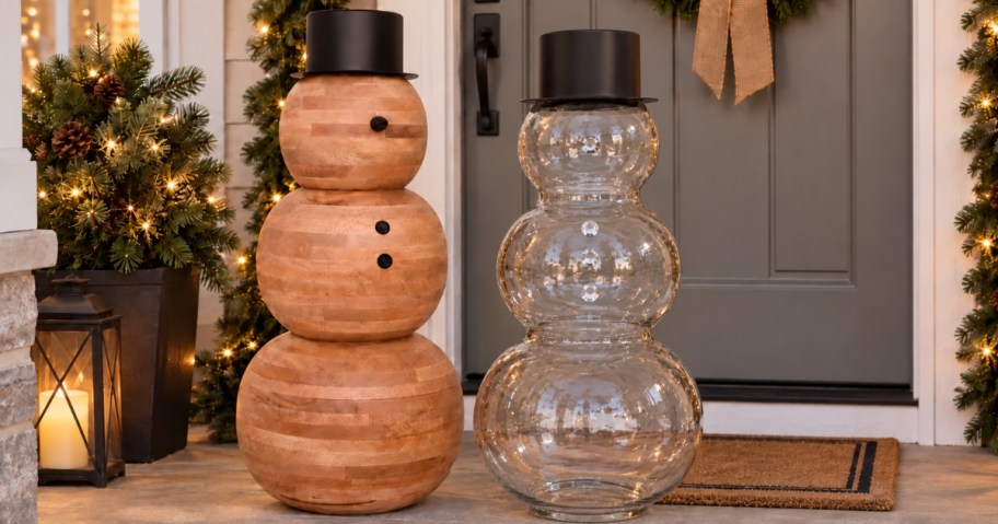 a wood and a glass snowman on a front porch decorated for Christmas