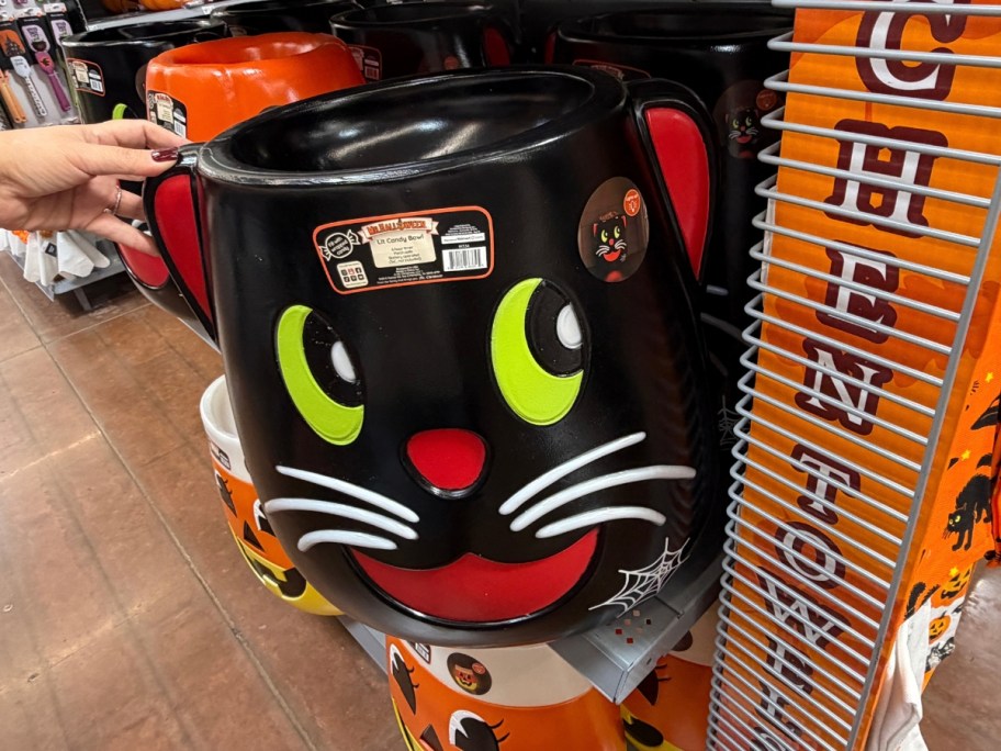 hand reaching for a black cat Halloween candy bowl blow mold on a store shelf