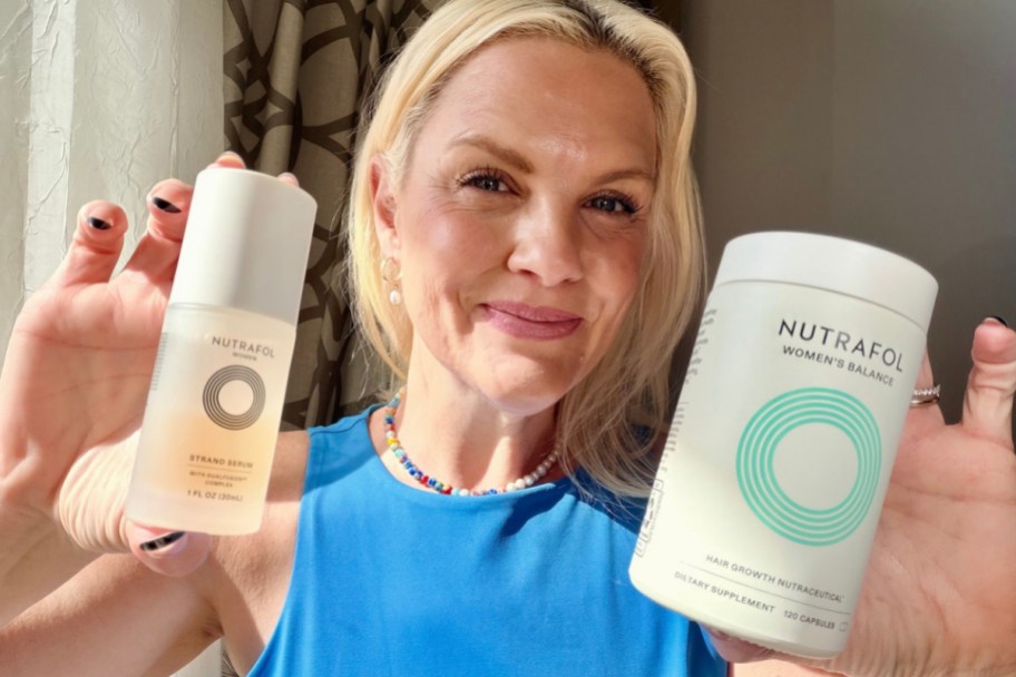 smiling woman holding a bottle of Nutrifol and a bottle of Strand Seum