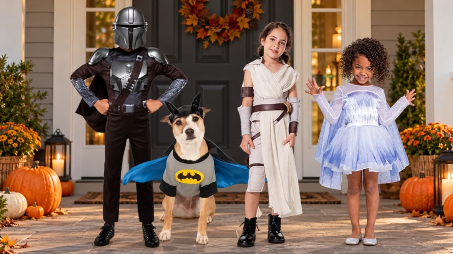 three kids and a dog wearing halloween costumes