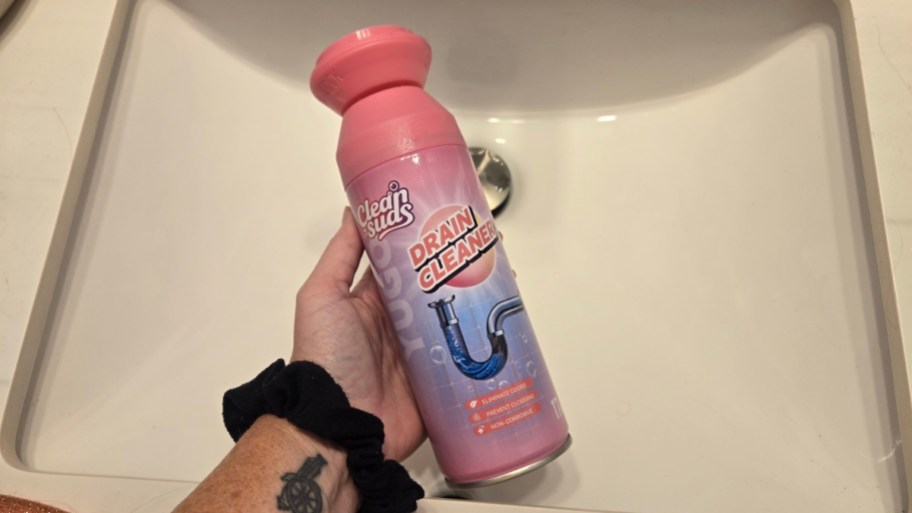 womans hand holding a can of foaming drain cleaner