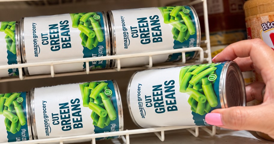 hand grabbing Amazon Grocery Canned Green Beans from pantry shelf