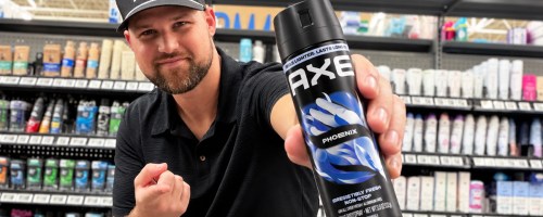 man holding up and pointing to a can of axe body spray