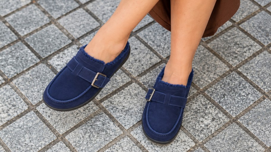 a woman wearing a pair of suede mules