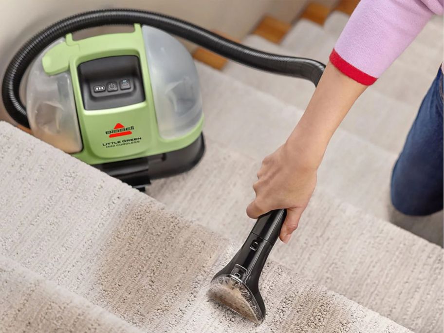 person using Bissell Little Green Mini Cordless Portable Carpet Cleaner on stairs