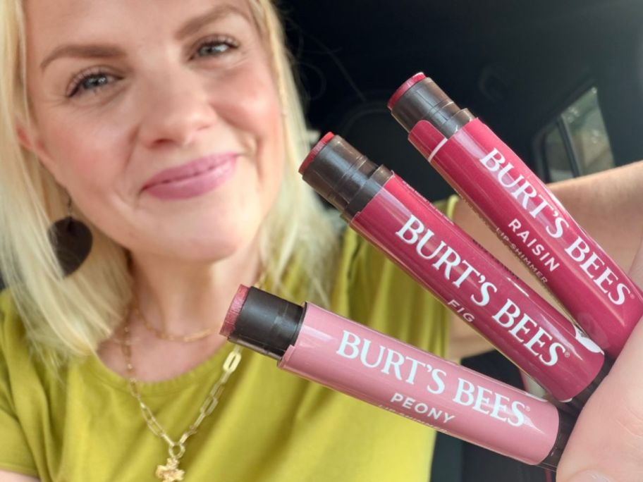 Woman holding 3 Burt's Bees Nude Lip Shimmers