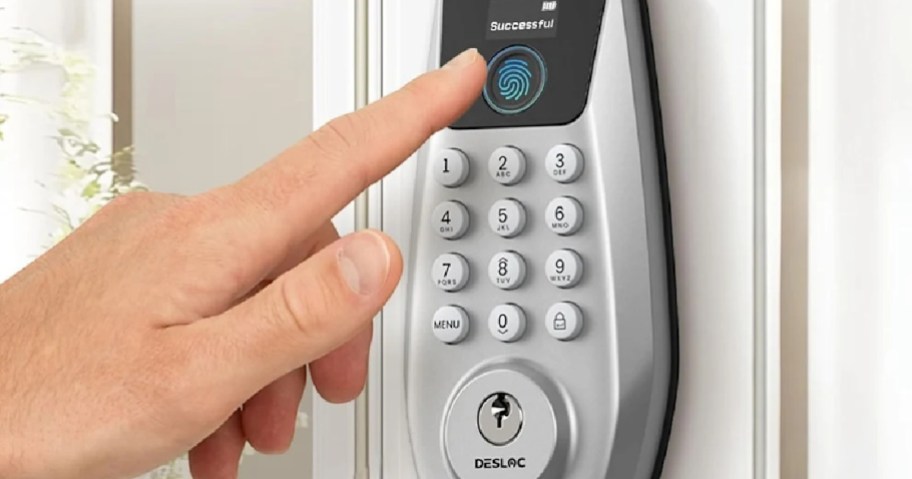 DESLOC C110 fingerprint smart deadbolt mounted on a door with a person's finger unlocking the device via the built-in biometric scanner above a numerical keypad.
