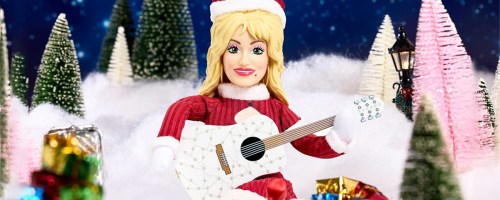 Dolly on the Holly Plush Doll sitting in fake snow with bottle brush trees