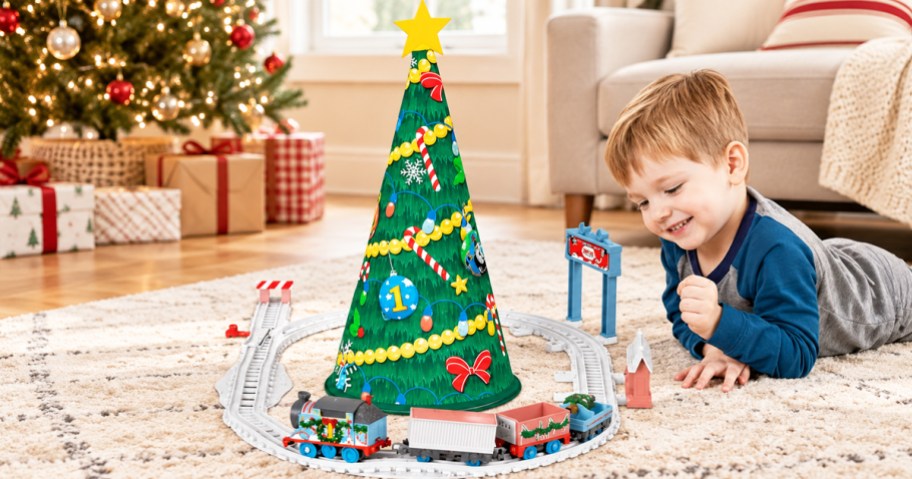 boy playing with thomas the train set going around a christmas tree