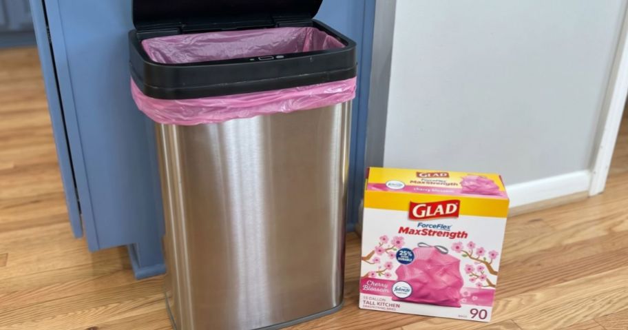 A Stainless Steel Trash Can with a pink trash bag and a box of Glad Pink Trash Bags next to it