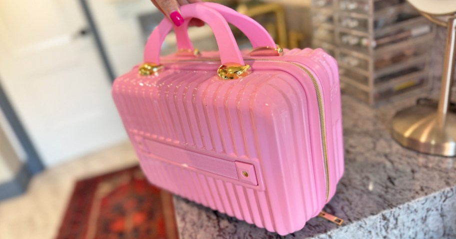 hand holding a pink hard shell cosmetics case