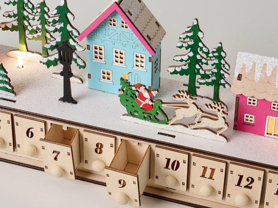 home reflections wooden christmas village advent calendar with drawers open and house with trees and santa on top