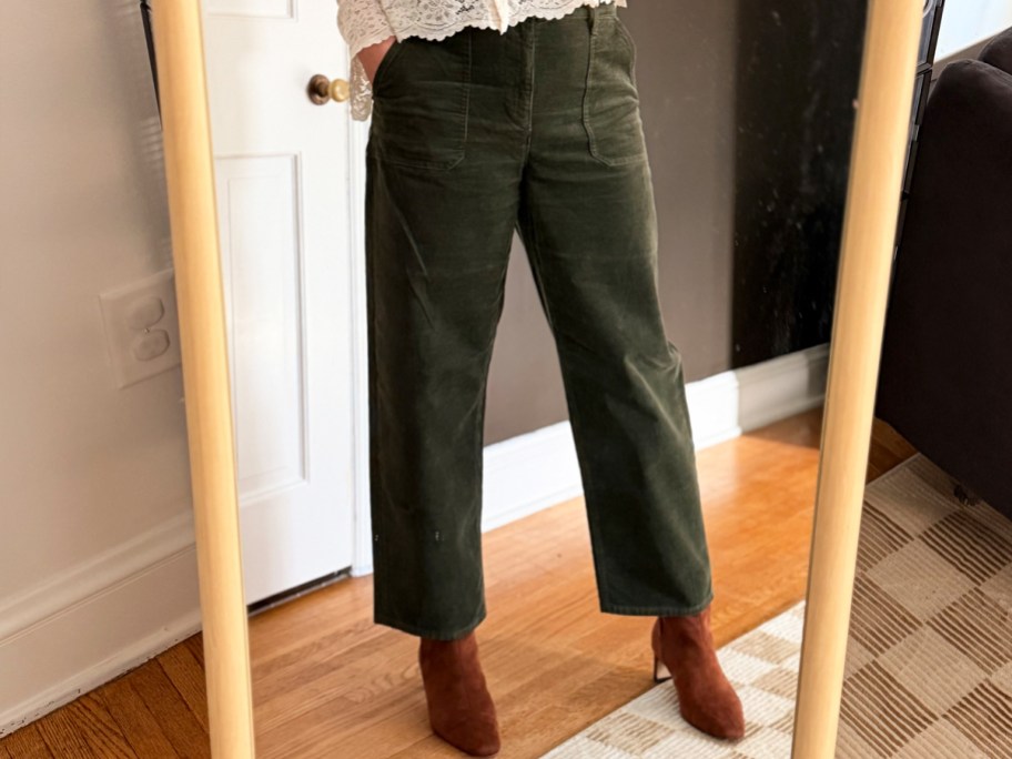 woman taking photo in mirror wearing green pants and brown boots