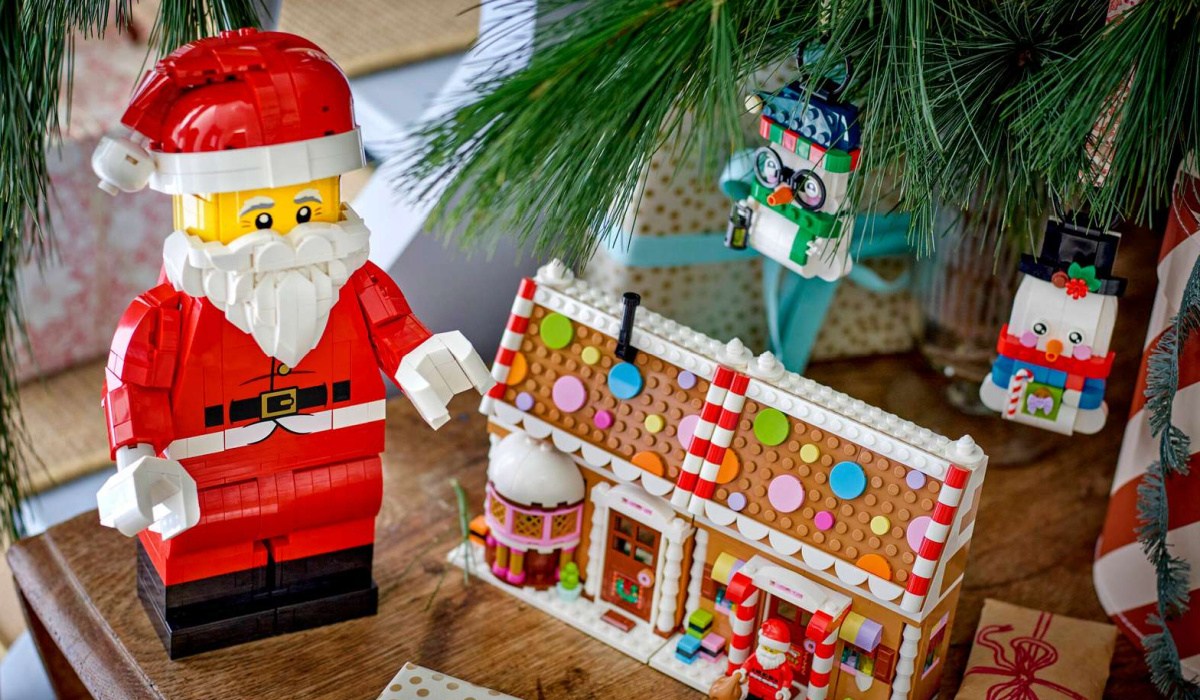 LEGO Santa Figure standing next to lego gingerbread house by christmas tree