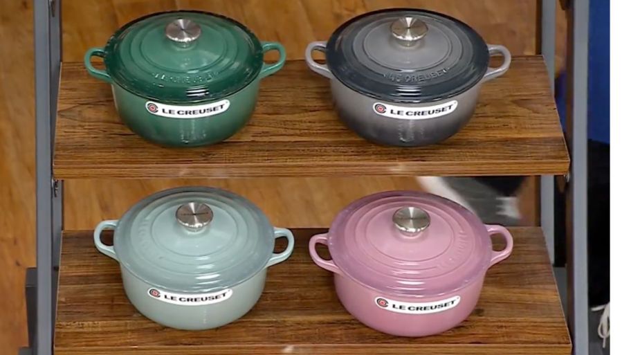 four different color Le Creuset displayed on a stand