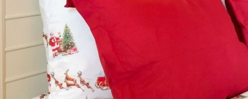 Linens & Hutch Holiday Sheets with Santa on a bed with red shams