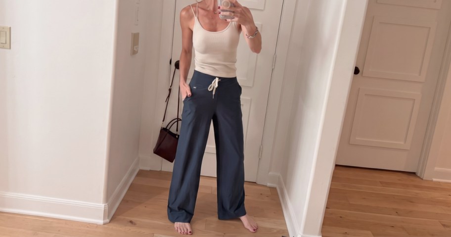 Woman wearing white sleeveless top and navy blue high-rise wide-leg pants in a hallway