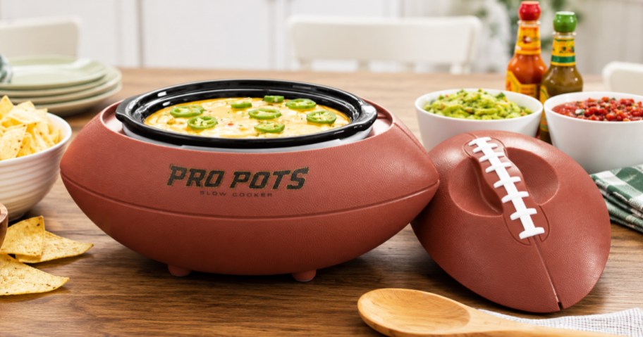 dip inside a football shaped slow cooker on a counter