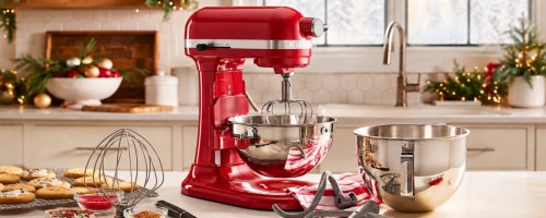 Red kitchen aid mixer on countertop next to baking utensils