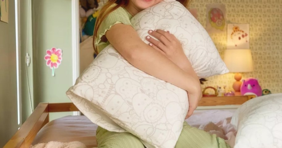 young girl holding squishpillow bed pillow in room