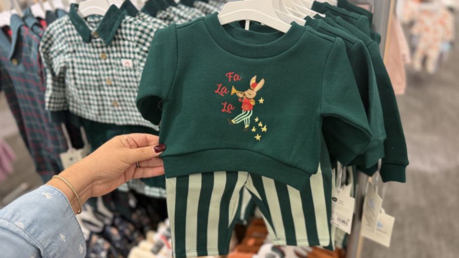 hand holding Target baby Christmas outfit with stripped pants