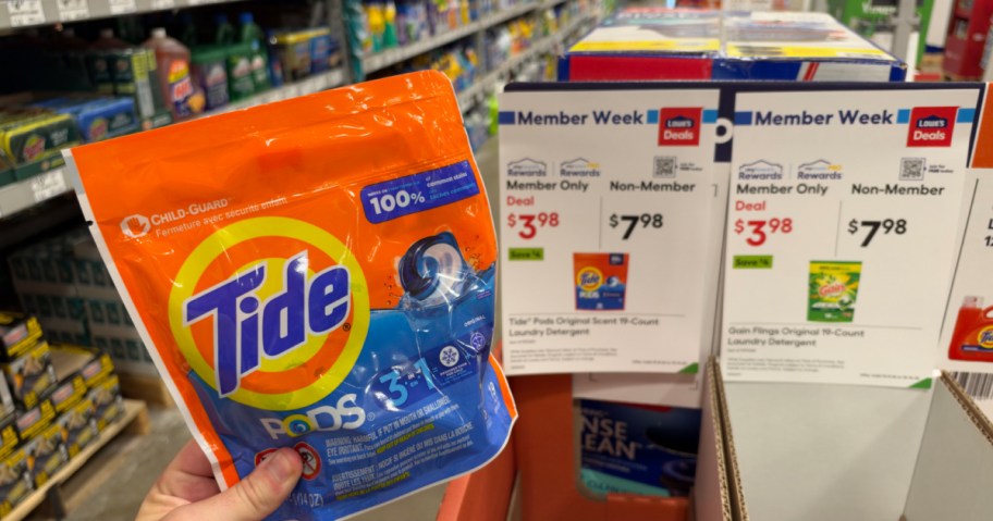 Tide Pods in hand in front of a sale sign