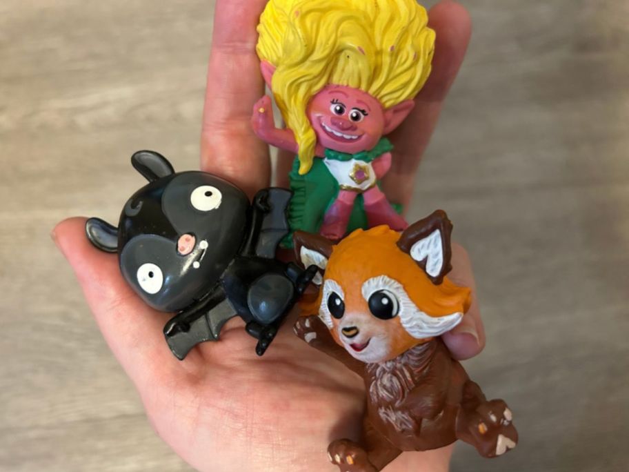 Hand holding Tonies Bat, Trolls 2 Viva and National Geographic Red Panda