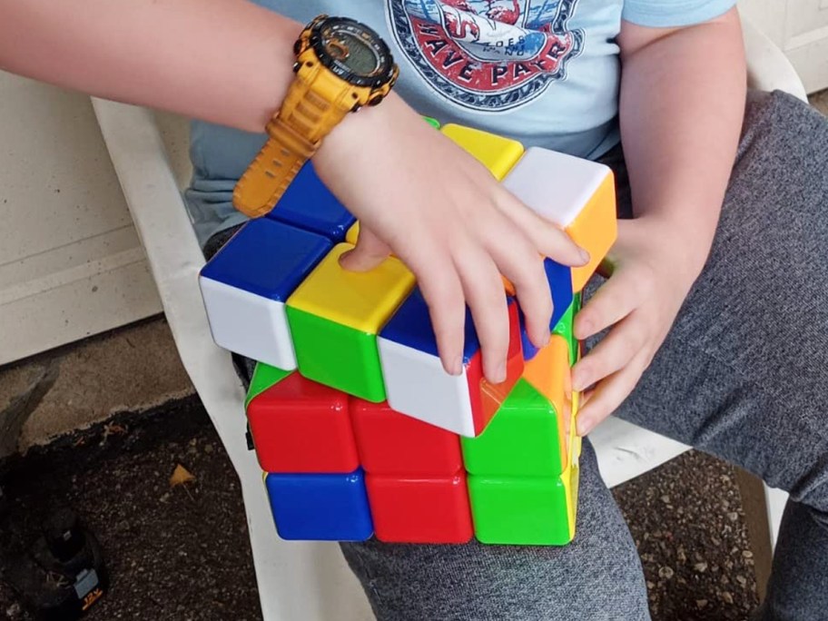 person solving a giant puzzle cube