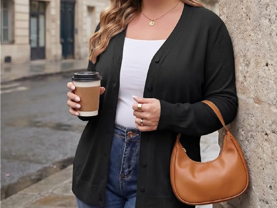women wearing a black cardigan and carrying coffee and a purse