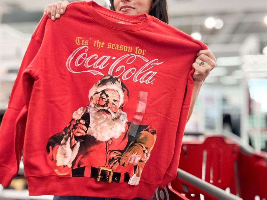 woman holding a coke christmas sweatshirt in-store
