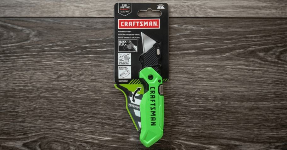 green utility knife on wooden surface