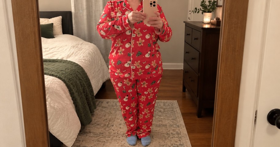 woman wearing red christmas pajamas and taking a selfie in a bedroom