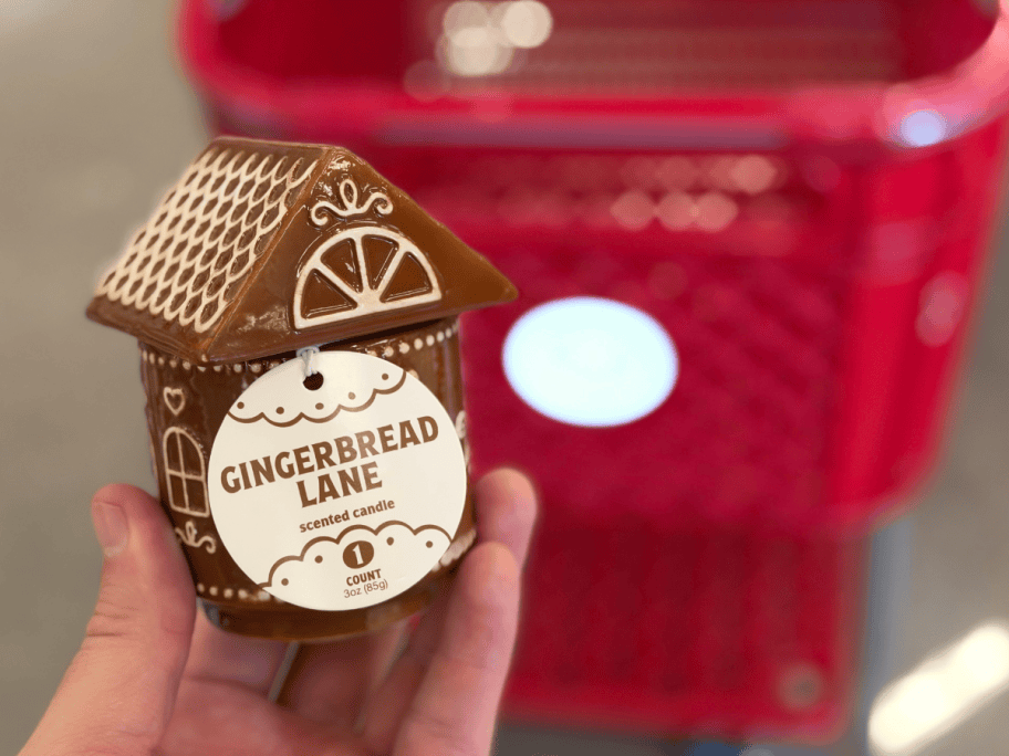 hand holding a gingerbread house candle by target cart