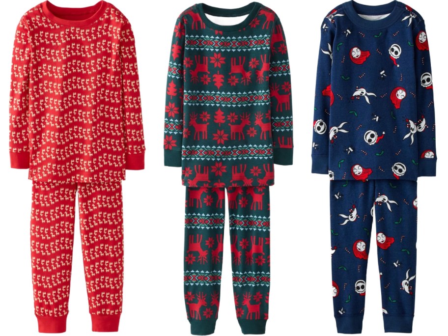 Three sets of children's long-sleeve holiday pajamas, featuring a red set with a small repeating reindeer print on the left, a dark green Nordic-style set with red reindeer and snowflake patterns in the center, and a navy blue set with a Nightmare Before Christmas character print on the right.