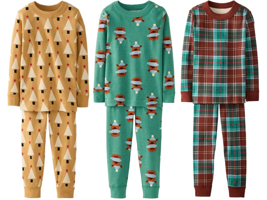 Three sets of children's long-sleeve pajamas, featuring a gold set with a white and red Christmas tree print on the left, a green set with a bear and fish print in the center, and a red, green, and brown plaid set on the right.