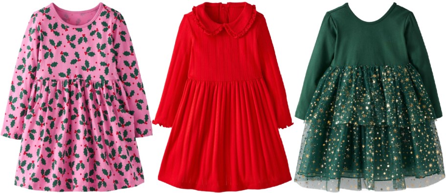 Three children's holiday dresses, featuring a pink long-sleeve dress with a green holly leaf and red berry print on the left, a solid red long-sleeve ribbed dress with a ruffled collar in the center, and a dark green long-sleeve dress with a tiered, sparkly gold star-printed tulle skirt on the right.