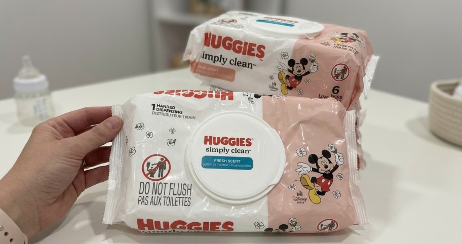 hand holding a pack of huggies baby wipes with more packs in the back