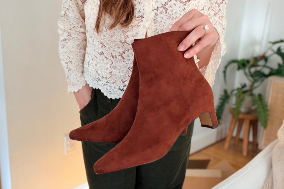 woman holding a pair of suede booties