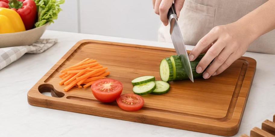 person cutting veggies on wood cutting board on countertop