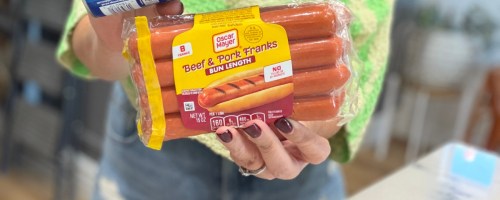 A package of Oscar Mayer bun length beef and pork franks held up by a person.