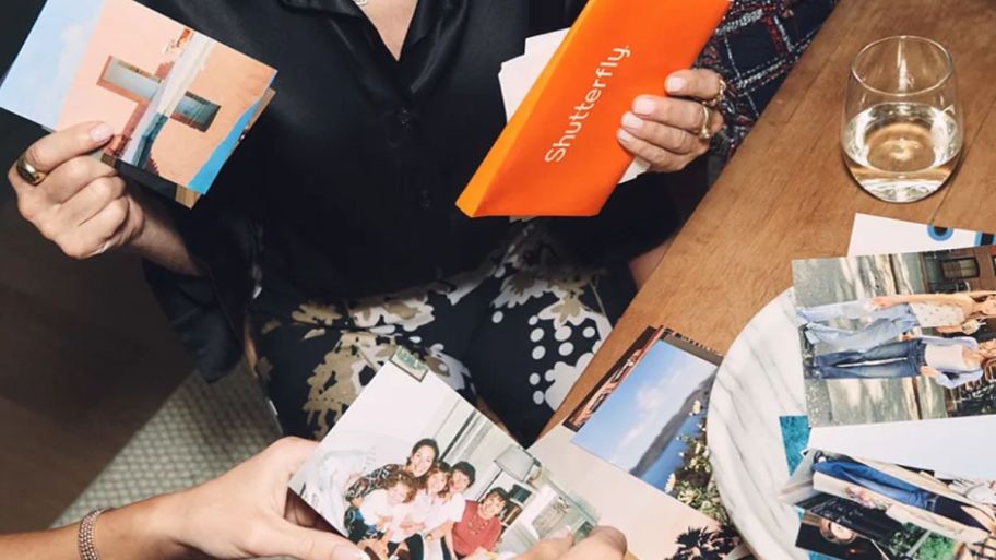 person holding photos in one hand and a shutterfly envelop in another