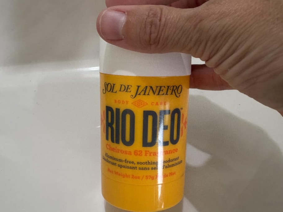 hand holding yellow deodorant tube