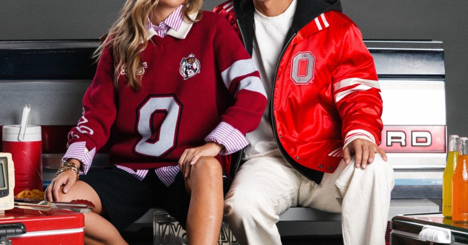Two people wearing Ohio State fan apparel: one in a burgundy sweater featuring a large number zero over a striped collared shirt, and the other in a bright red satin jacket with a "O" logo paired with a white t-shirt and light pants.