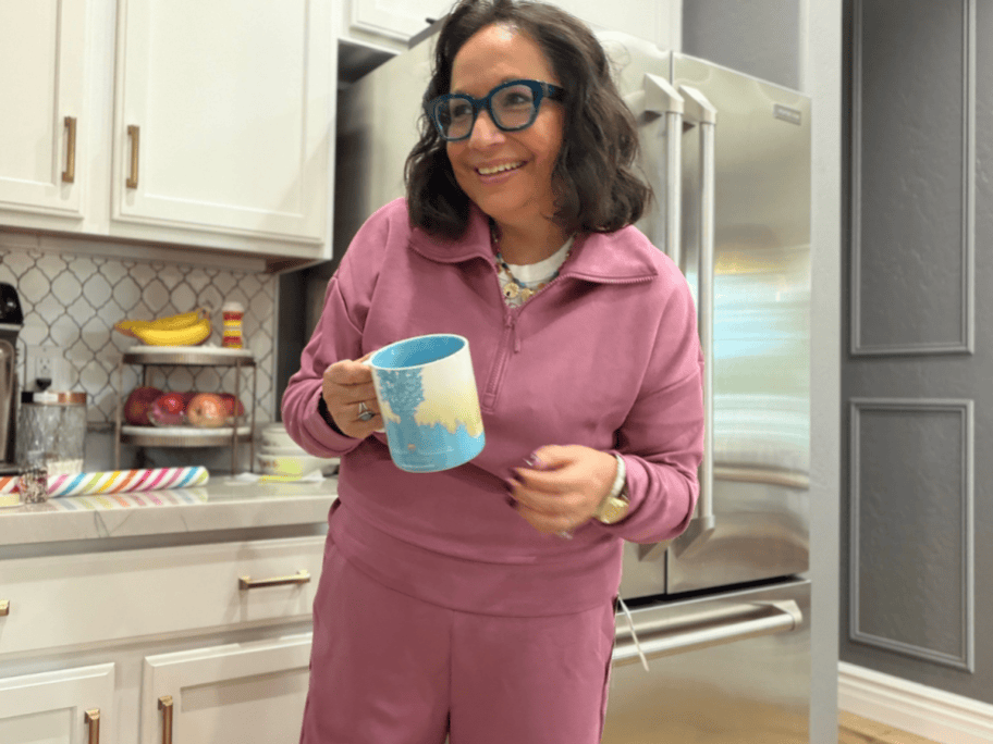 woman wearing scuba knit loungewear in a kitchen holding a coffee cup