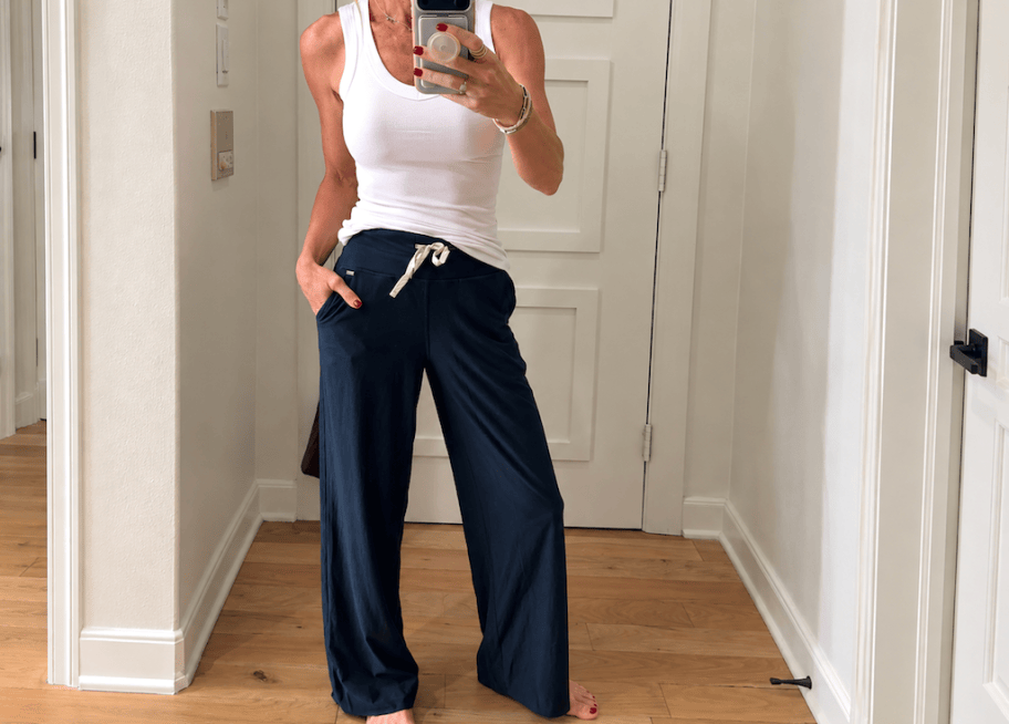 woman in white tank taking mirror selfie
