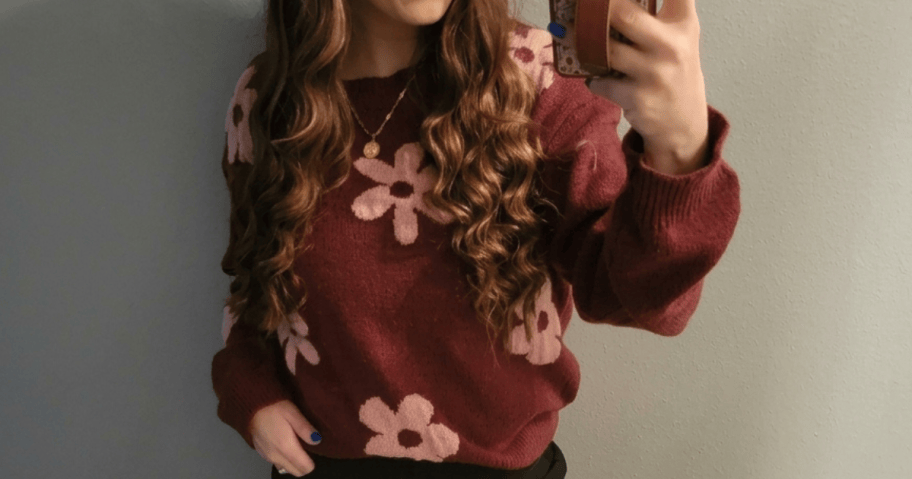 woman wearing a wine and pink flower sweater and taking a selfie